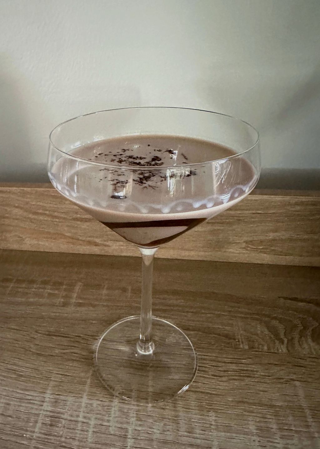 Baileys Chocolate Martini cocktail recipe on a marble countertop, garnished with cocoa powder and chocolate shavings.